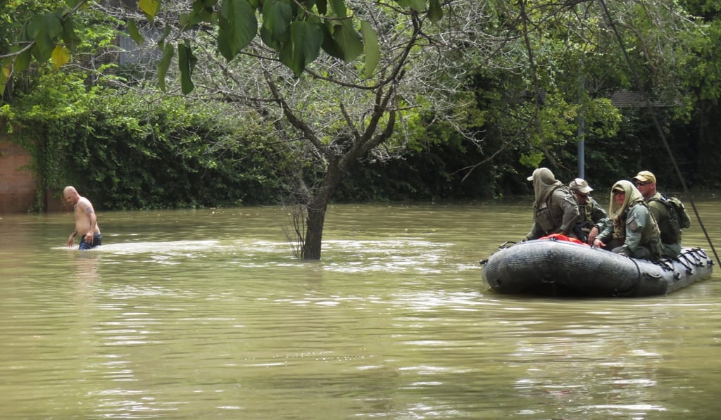 Texas Rangers in a boat help a man look for his drone after it crashed into flood waters in the west Houston. Photo: EPA