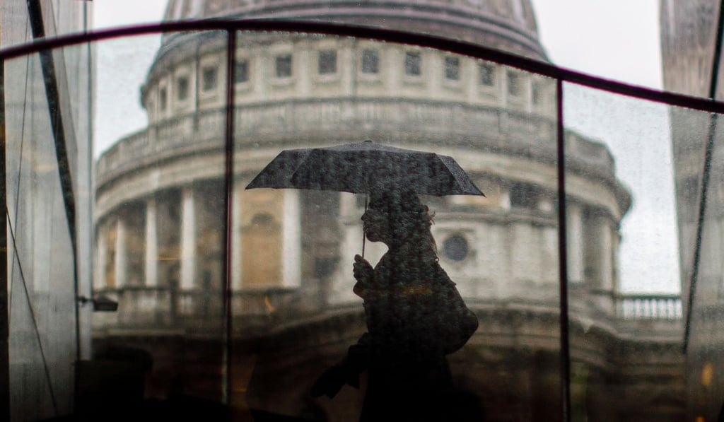 Pedestrians shelter from the rain beneath umbrellas as rain falls near St Paul's Cathedral in central London. Photo: AFP