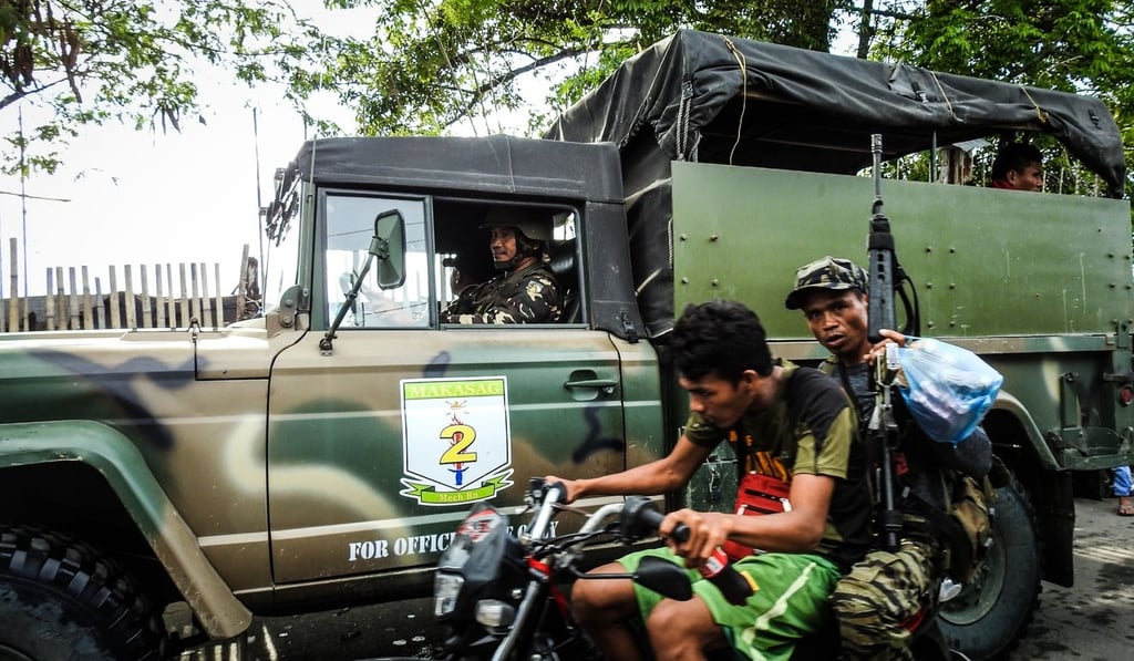 A Moro Islamic Liberation Front (MILF) rebel aboard a motorcycle, speed past a military vehicle in Datu Salibo town, Maguindanao province, in southern island of Mindanao. Photo: AFP