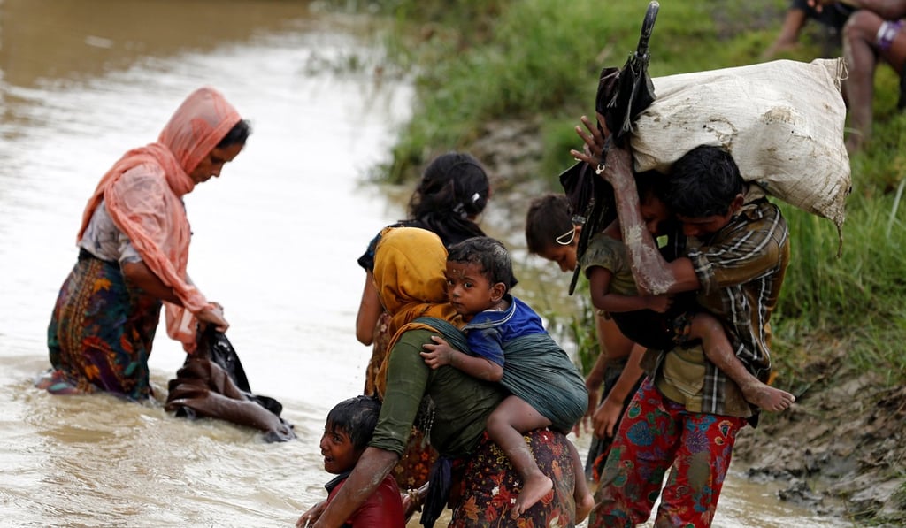Rohingya refugees wash mud from their clothes while crossing a canal in Teknaf, Bangladesh. Photo: Reuters