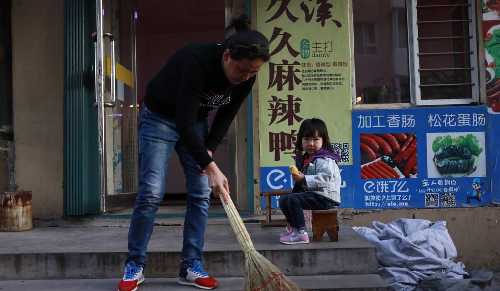 A Chinese girl looks on as a woman sweeps the steps of a shop in Baishan city on August 30. Sooner or later, the Chinese economy will stop growing. Photo: EPA