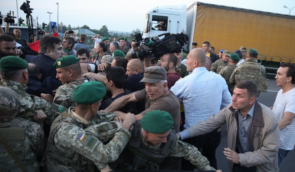 Supporters of former Georgian president Mikhail Saakashvili (left, in dark jacket) fight with Ukrainian border guards as Saakashvili crosses the Polish-Ukrainian border on Sunday. Photo: EPA