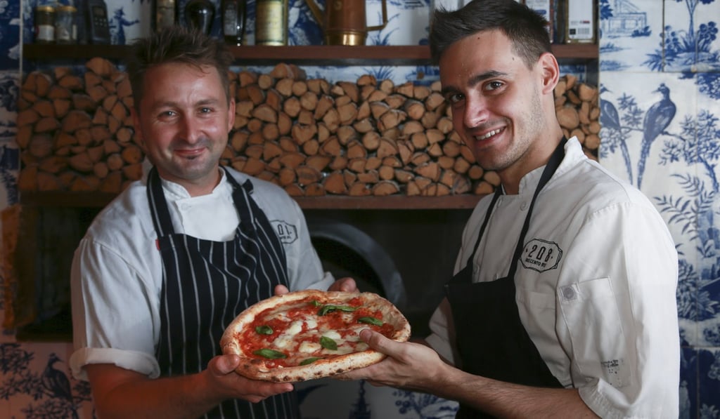 Chefs Michael Bolam (left) and Zeno Bevilacqua hold a margarita pizza at 208 Duecentro Otto. Photo: James Wendlinger