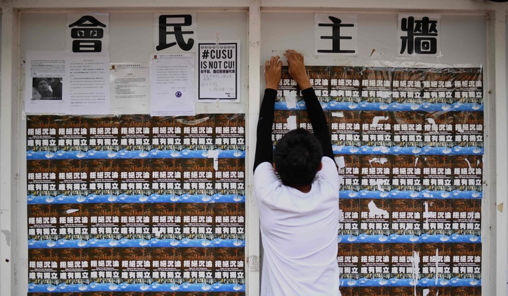 A student union member removes pro-Hong Kong independence posters to make space for other students to display notices at the Chinese University of Hong Kong on September 7. Photo: AFP
