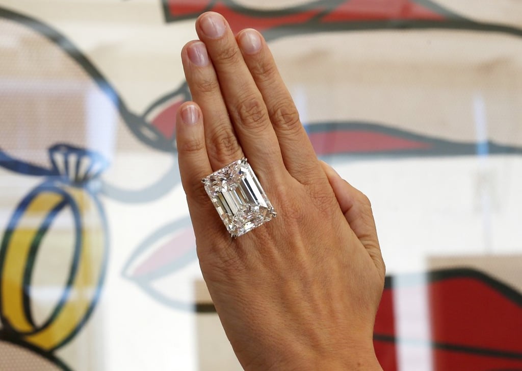 A woman displays a 100.20-carat diamond ring in front of Roy Lichtenstein's 1962 painting