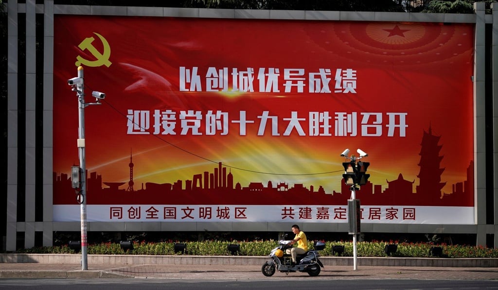 A man rides an electric scooter past a poster promoting the 19th Party Congress, in Shanghai, last week. Photo: Reuters