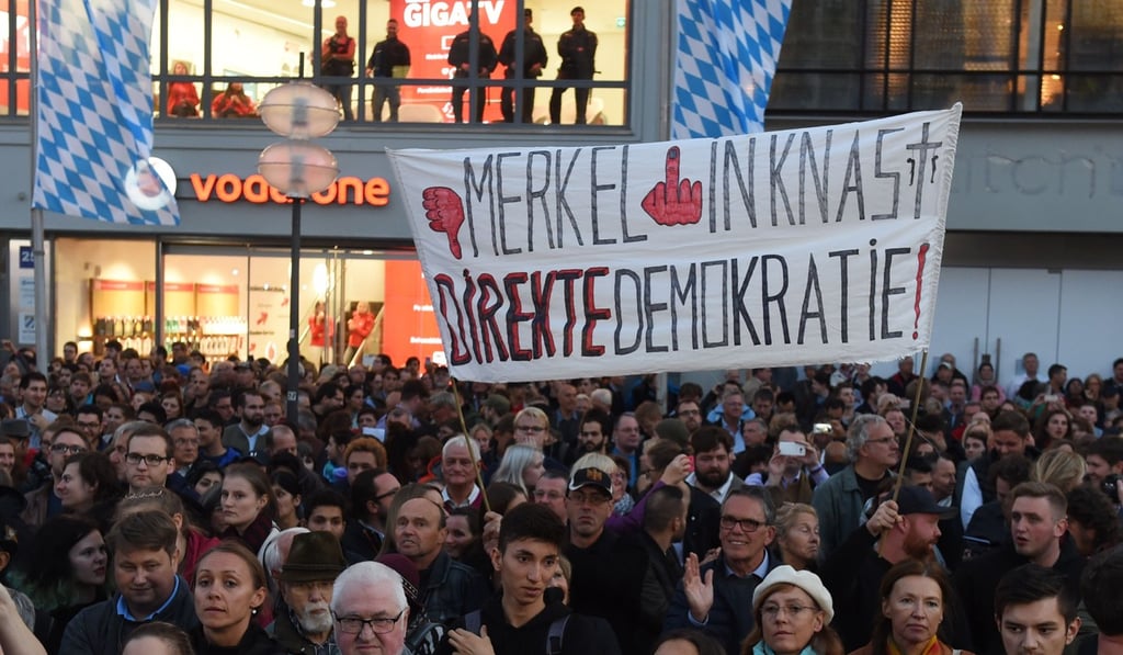 Opponents of Angela Merkel hold up a banner calling for her to be sent to jail during her final rally ahead of Sunday’s election. Hard right protesters heckled at the German chancellor, telling her to ‘get lost’. Photo: AFP