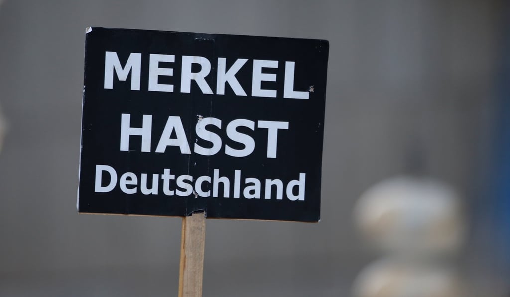 Protesters hold a sign reading ‘Merkel hates Germany’ during German Chancellor Angela Merkel’s final election rally in Munich. Photo: Reuters