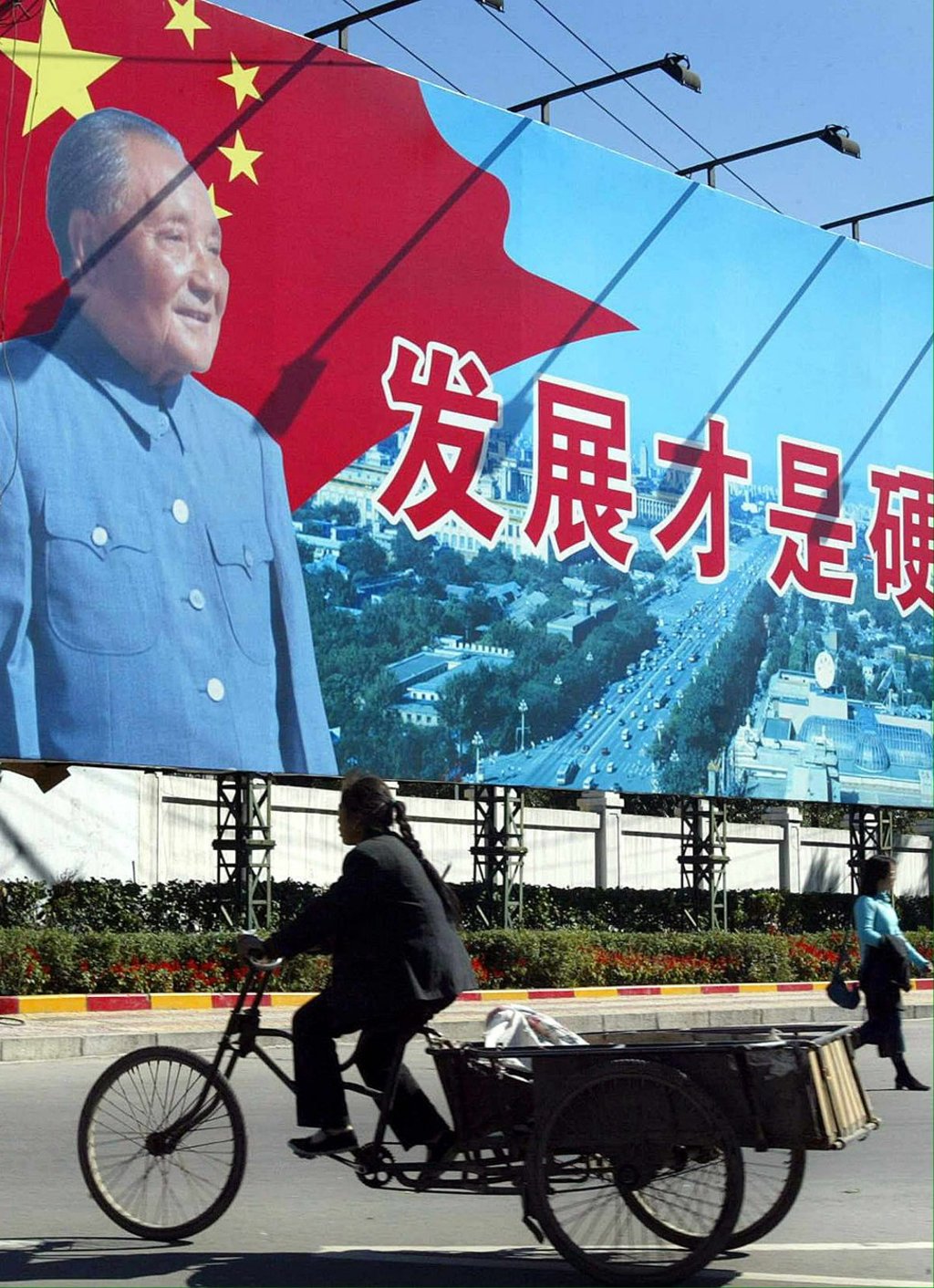 A woman rides past a billboard featuring Deng Xiaoping calling for modern development in October 2003, in Harbin, Heilongjiang province. Economic reforms since 1978 have helped market forces take huge strides towards becoming the dominant factor in the Chinese economy. Photo: AFP