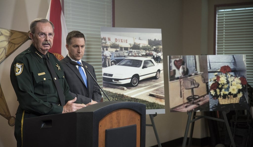 Palm Beach County Sheriff Ric Bradshaw speaks to reporters as Palm Beach County State Attorney Dave Aronberg looks on during a news conference at the Palm Beach County Sheriff's Office about the 1990 fatal shooting of a Florida woman by an assailant dressed as a clown. Photo: AP Palm Beach County Sheriff Ric Bradshaw speaks to reporters as Palm Beach County State Attorney Dave Aronberg looks on during a news conference at the Palm Beach County Sheriff's Office about the 1990 fatal shooting of a Florida woman by an assailant dressed as a clown. Photo: AP
