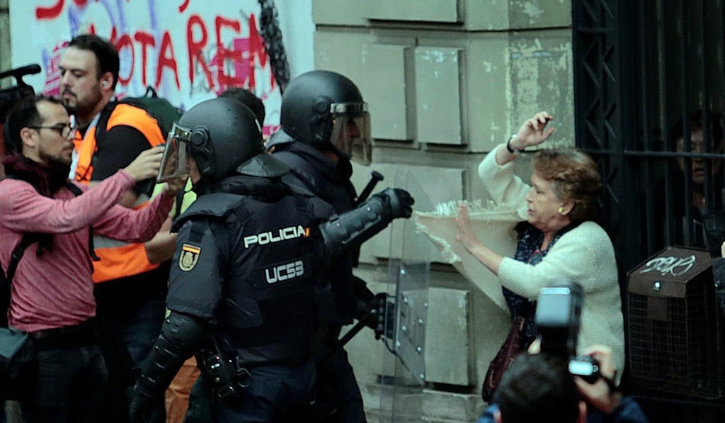 A woman is grabbed by a riot police officer near a polling station for the banned independence referendum in Barcelona, Spain. Photo: Reuters