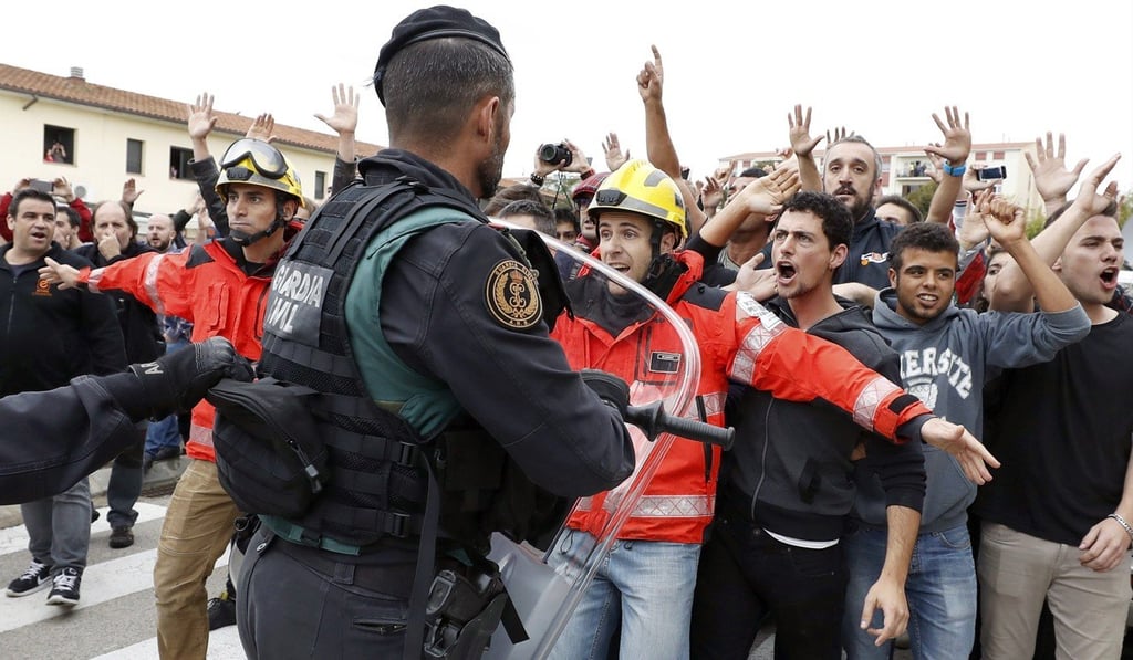 Firefighters stand between pro-independence Catalans and riot police at Sant Julia de Ramis sports centre near Girona on Sunday. Photo: EPA Firefighters stand between pro-independence Catalans and riot police at Sant Julia de Ramis sports centre near Girona on Sunday. Photo: EPA