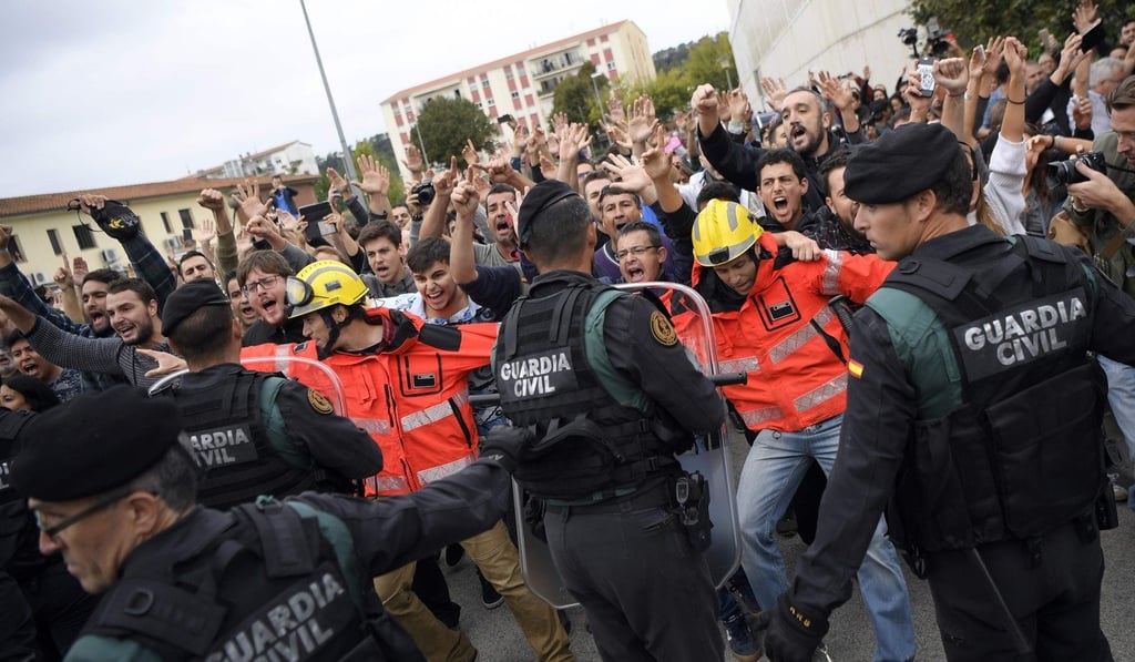 Firefighters stand between pro-independence Catalans and riot police at Sant Julia de Ramis sports centre near Girona on Sunday. Photo: AFP Firefighters stand between pro-independence Catalans and riot police at Sant Julia de Ramis sports centre near Girona on Sunday. Photo: AFP