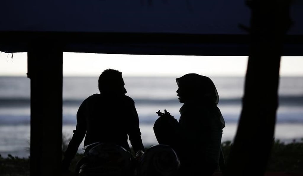 A young couple chat in the shade on a beach in Indonesia. Photo: Reuters