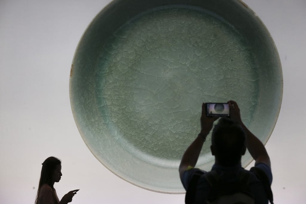 An auction-goer photographs an image of the Ru brush washer projected on a screen at the Sotheby’s sale in Hong Kong. Photo: Dickson Lee