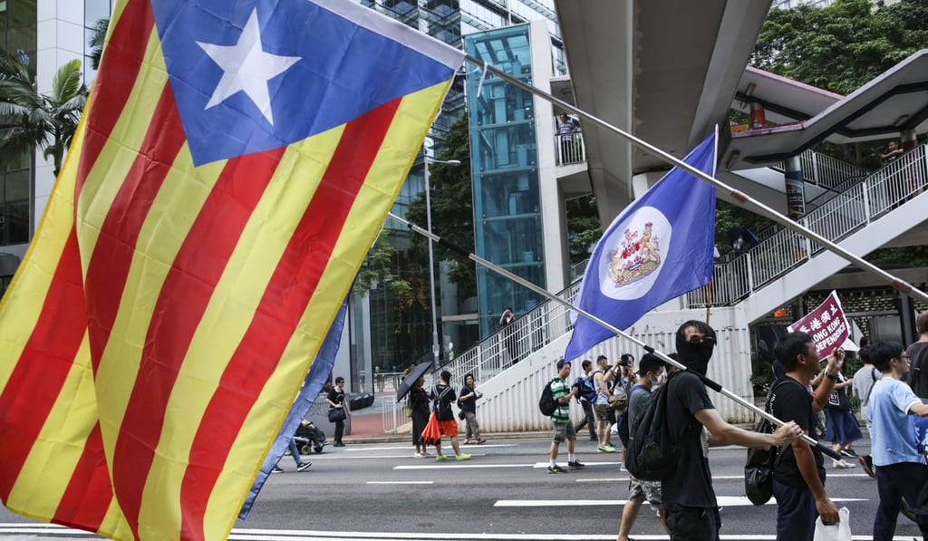 Protesters carry the Catalonia independence movement flag and Hong Kong colonial flag during a rally from Victoria Park in Causeway Bay to the government headquarters in Tamar on Sunday. Photo: Sam Tsang