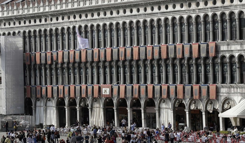 Tourists walk in St Mark's square in Venice, Italy, on Wednesday, October 4, 2017. British architect David Chipperfield is bringing his expertise in restoring historic buildings to the 500-year-old Procuratie Vecchie building on the northern edge of the square. Photo: AP Tourists walk in St Mark's square in Venice, Italy, on Wednesday, October 4, 2017. British architect David Chipperfield is bringing his expertise in restoring historic buildings to the 500-year-old Procuratie Vecchie building on the northern edge of the square. Photo: AP