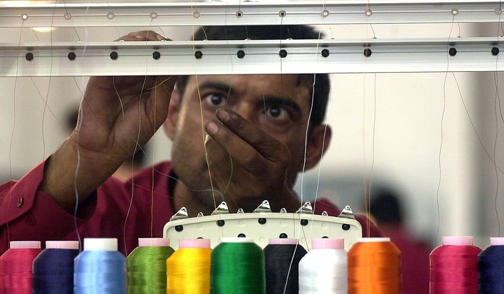 A textile worker threads an embroidery machine. Photo: AFP