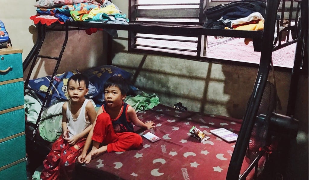 Two of Manuel S. Adad’s three sons sit in their family home, which is made up of just two bedrooms, with four bunk beds and some mattresses on the floor. Photo: Karim Raslan