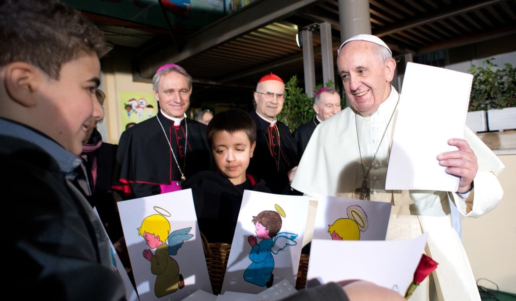 Pope Francis talks to children during his visit at the Bambino Gesu Paediatric Hospital in Rome. In the background are Archbishop Georg Gaenswein (left) and Cardinal Tarcisio Bertone (centre). Photo: AP