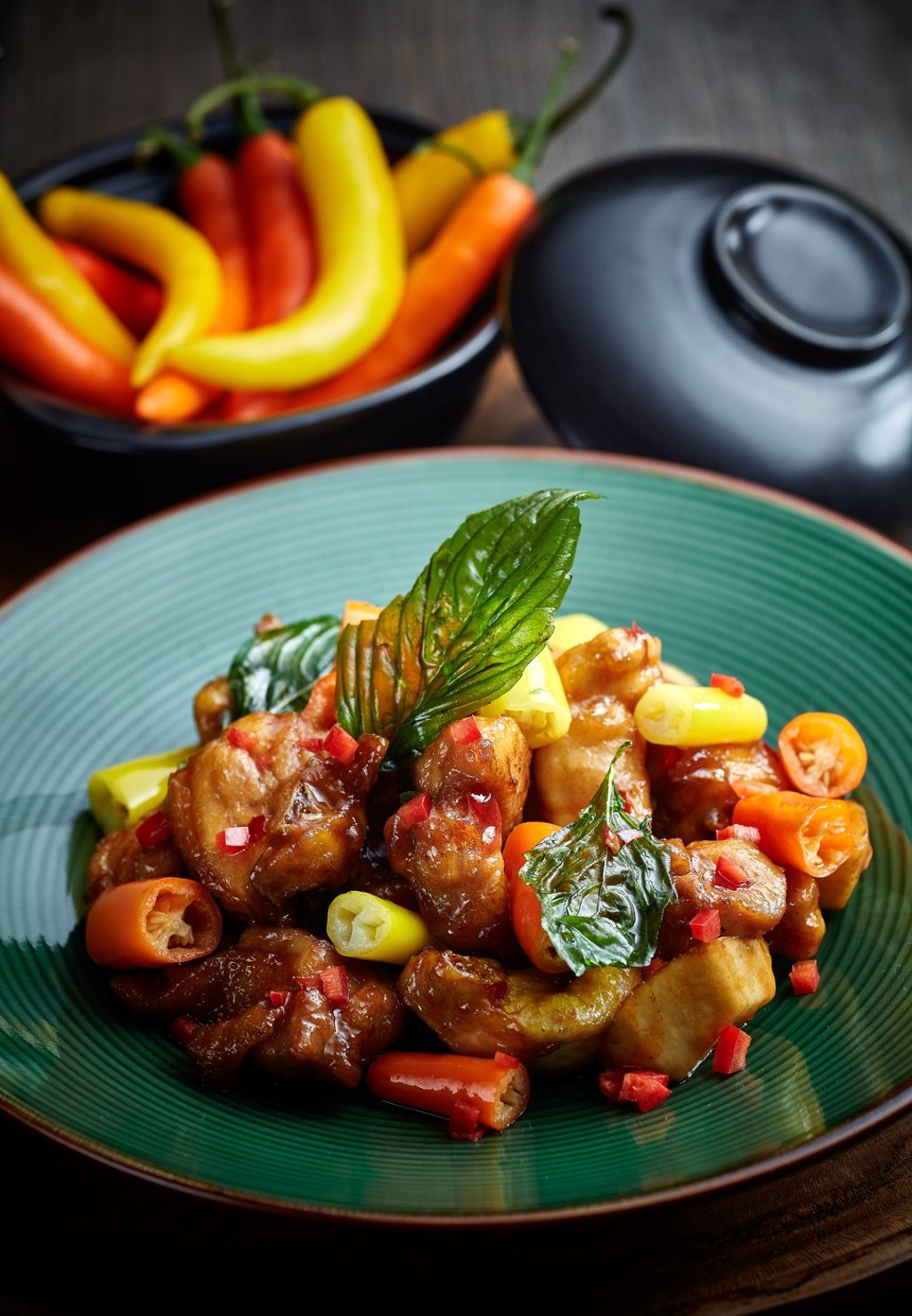 Fried chicken with orange and yellow cayenne chilli peppers in a clay pot at Yue.