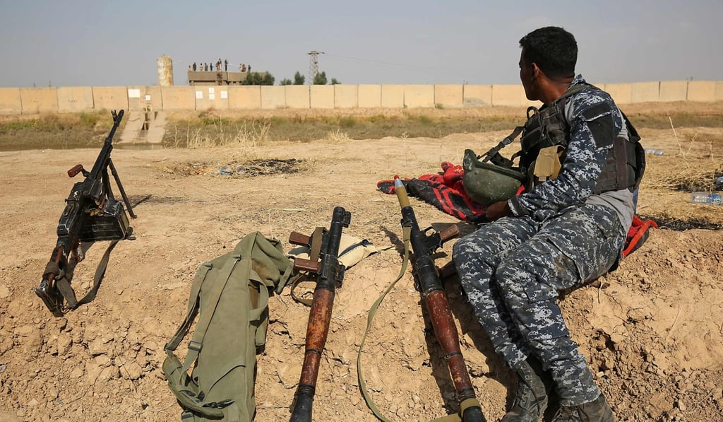 A member of the Iraqi forces sits on a river bank across from Kurdish peshmerga positions on October 15, 2017, on the outskirts of Kirkuk. Photo: AFP