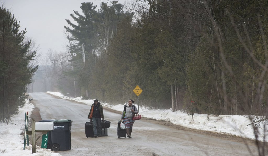 Two asylum seekers claiming to be from the Democratic Republic of Congo walk on a country road in the United States to cross into Canada on March 28, 2017, near Hemmingford, Quebec. Photo: AP