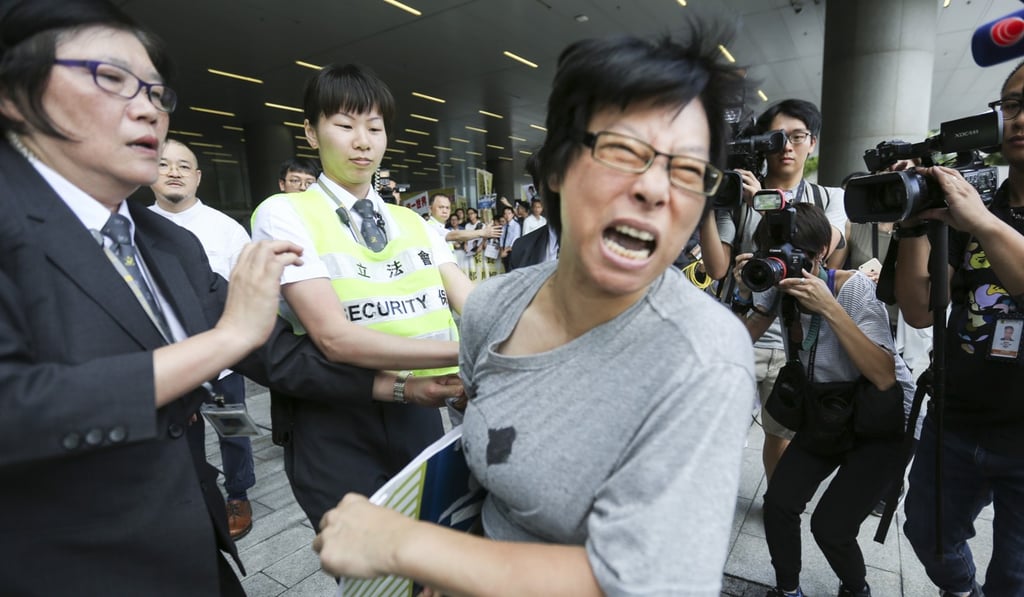 A protester trying to appeal to Hong Kong Chief Executive Carrie Lam Cheng Yuet-ngor over universal retirement protection struggles with a security guard outside the Legislative Council in Tamar in July. Photo: Xiaomei Chen
