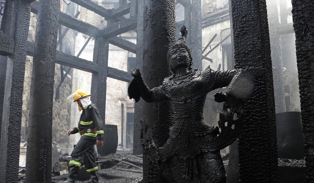 A firefighter walks through the burnt remains of the hotel. Photo: AP A firefighter walks through the burnt remains of the hotel. Photo: AP