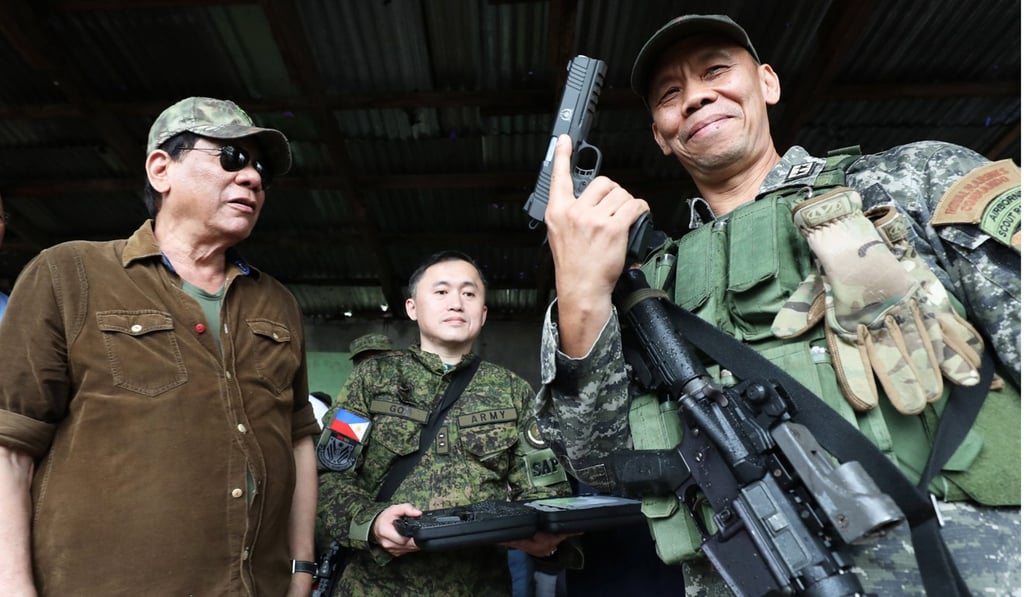 Duterte looking at a soldier holding a pistol during his visit to the war-torn city of Marawi. Photo: EPA Duterte looking at a soldier holding a pistol during his visit to the war-torn city of Marawi. Photo: EPA