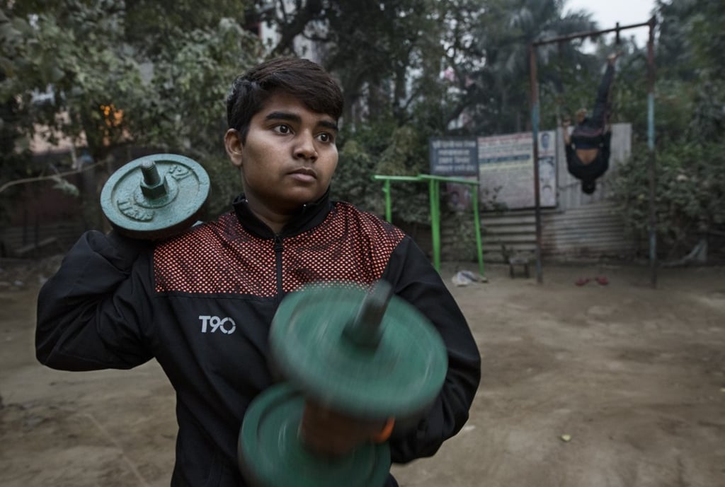 A young female kushti wrestler lifts weights during an early morning training session in Delhi.