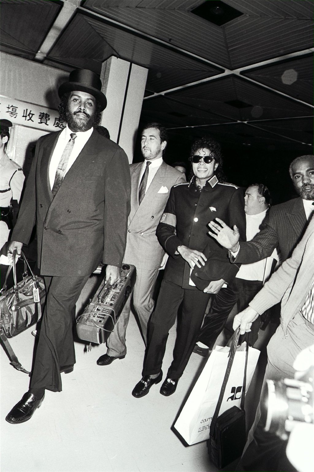 Flanked by bodyguards, Michael Jackson arrives at Kai Tak airport on November 10, 1987 following his stay in Hong Kong and a trip to China, to fly to Sydney. Picture: David Wong