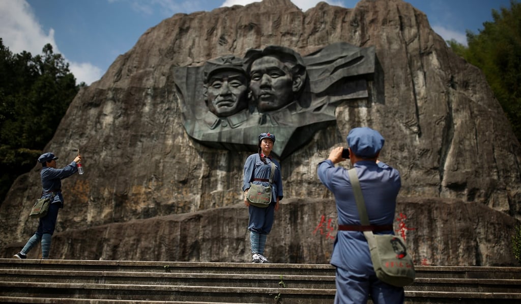 Chinese dressed in replica red army uniforms take pictures at a base relief showing former Chinese Communist leaders Mao Zedong and Zhu De at a historic site of the Long March in the mountains outside Jinggangshan, Jiangxi province, on September 14. Photo: Reuters