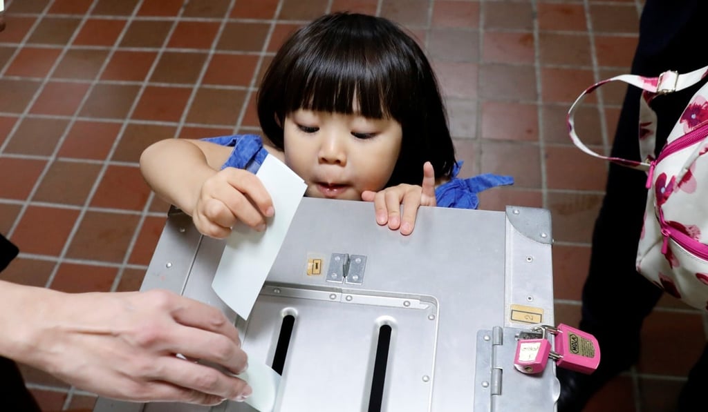 A girl casts her father's ballot for the national election at a polling station in Tokyo. Photo: Reuters