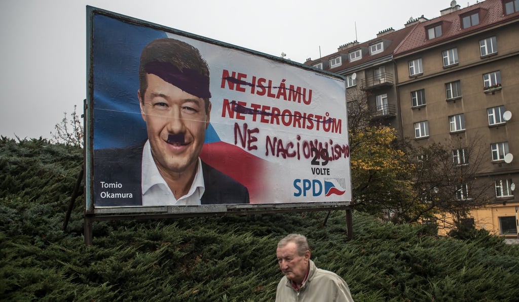 A man walks past defaced election poster of Tomio Okamura, leader of the Freedom and Direct Democracy party, in Prague, Czech Republic. Photo: EPA