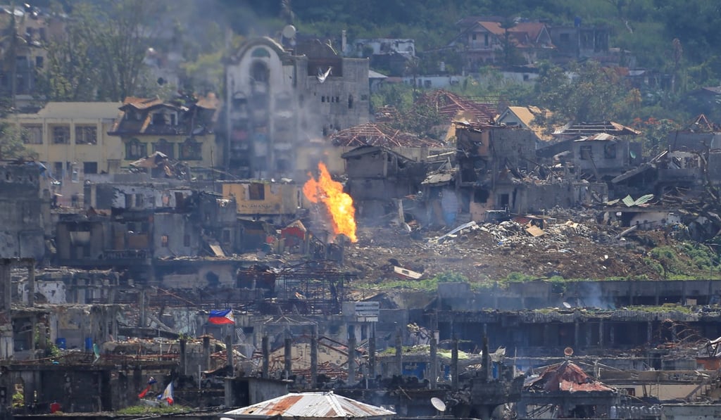 Flames rise from damaged buildings inside a war-torn area of Marawi city, southern Philippines. Photo: Reuters
