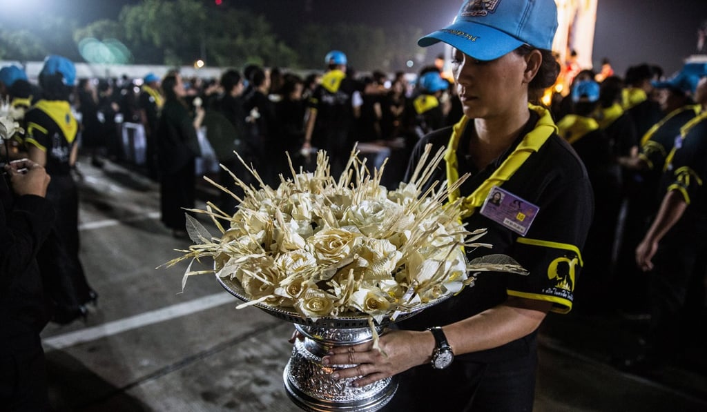 A volunteer offers sandalwood flowers to mourners during the cremation ceremony of the late King Bhumibol Adulyadej at the Royal Plaza in Bangkok, Thailand, on Thursday. Photo: Bloomberg