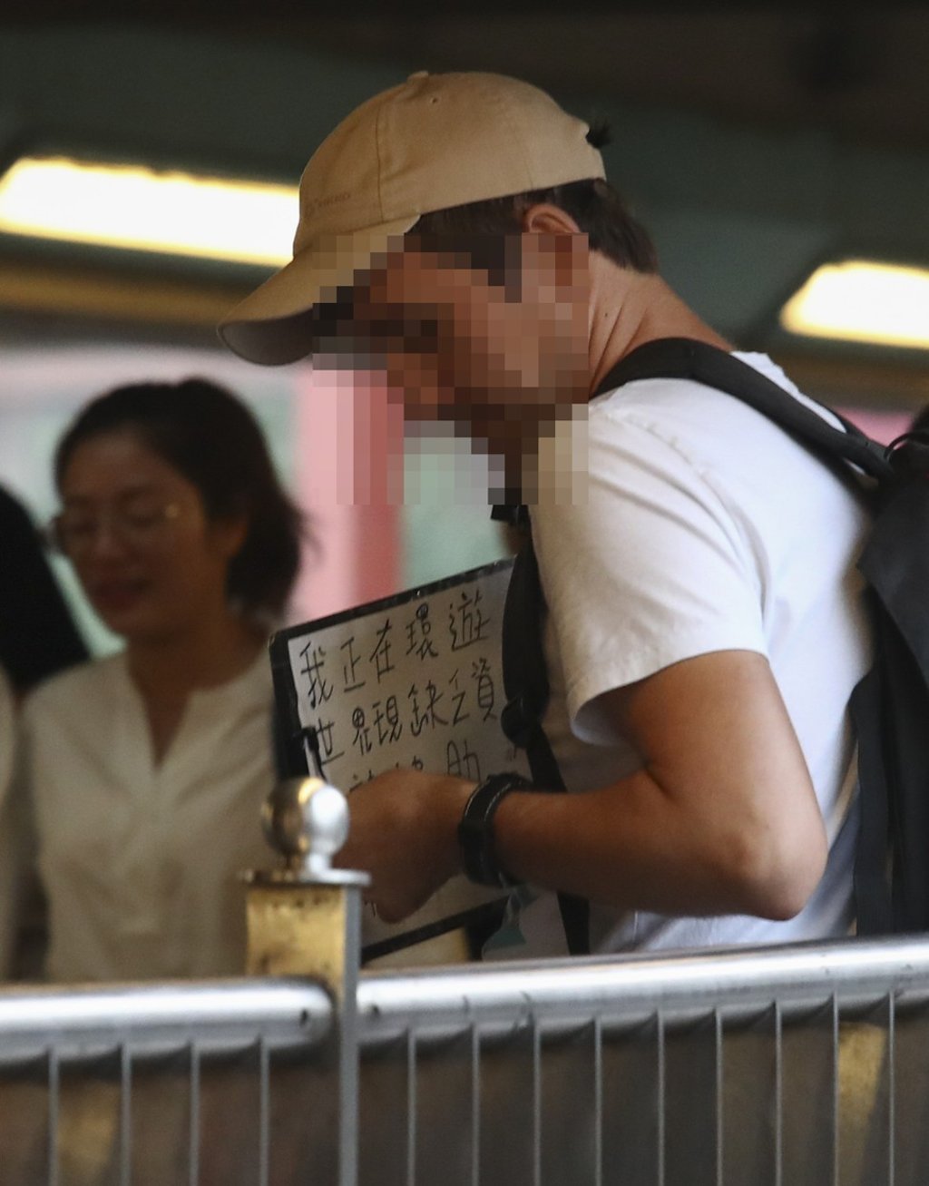 The sign reads, “I’m travelling on a world trip, but don’t have enough money [...] Please help!” Picture: Nora Tam