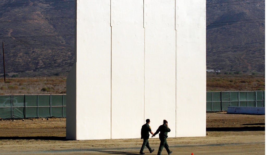 US border patrol officers walk near a prototype for US President Donald Trump's border wall on Thursday. Photo: Reuters