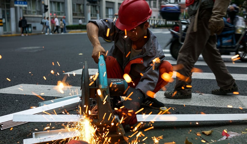 A Chinese construction worker cuts aluminium panels by a roadside in Shanghai. Photo: Agence France-Presse