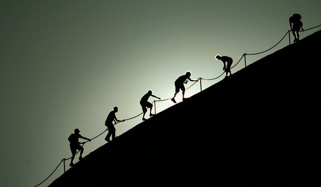 Tourists use a chain to climb the rock known as Uluru, also called Ayers Rock. File photo: Reuters