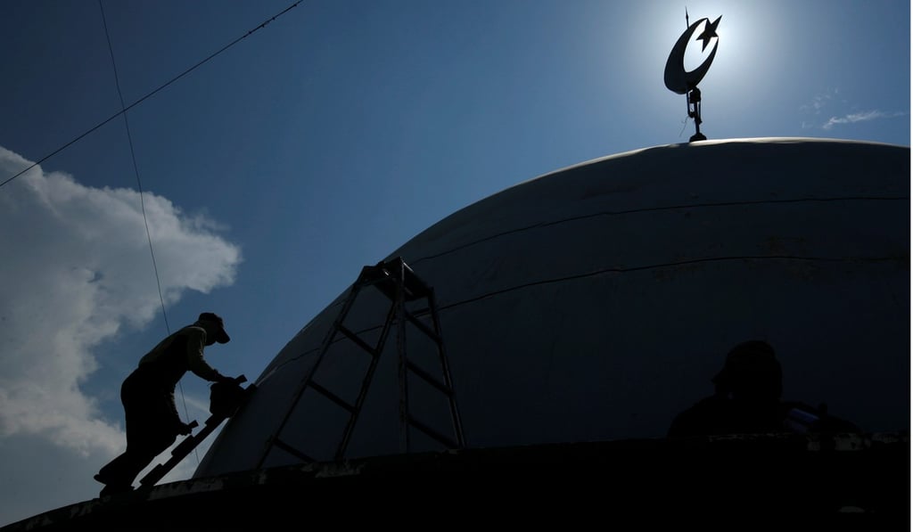 A worker paints the top of a mosque near Lamongan in East Java province. Photo: Reuters