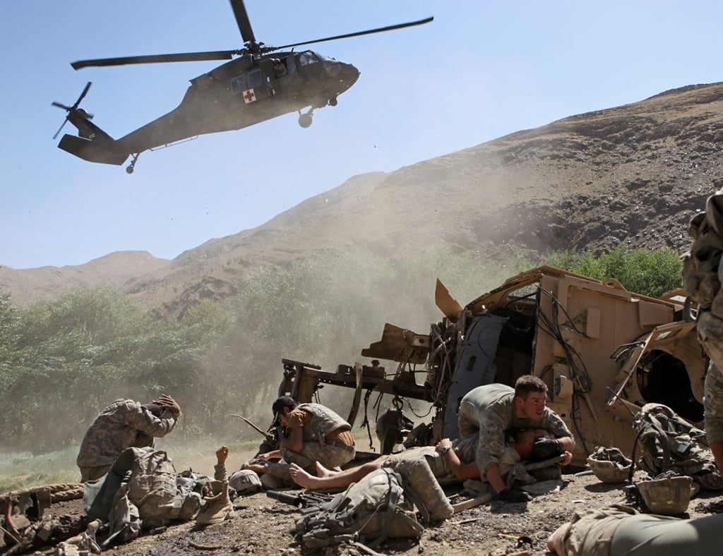 US soldiers take cover as a helicopter lands to evacuate the wounded after a unit’s armoured vehicle hit a roadside bomb in the Tangi Valley of Afghanistan's Wardak Province. Photo: AP