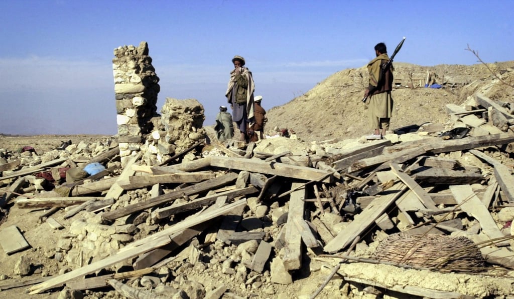 Residents of Kama Ado, Afghanistan, survey the damage to a house in December, 2001, where locals said 17 members of one family were killed in a US bombing raid. Photo: AP