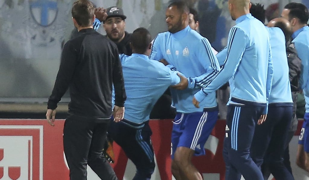 Patrice Evra raises his foot to kick a man during a scuffle with Marseille supporters who trespassed into the pitchside area. Photo: AP