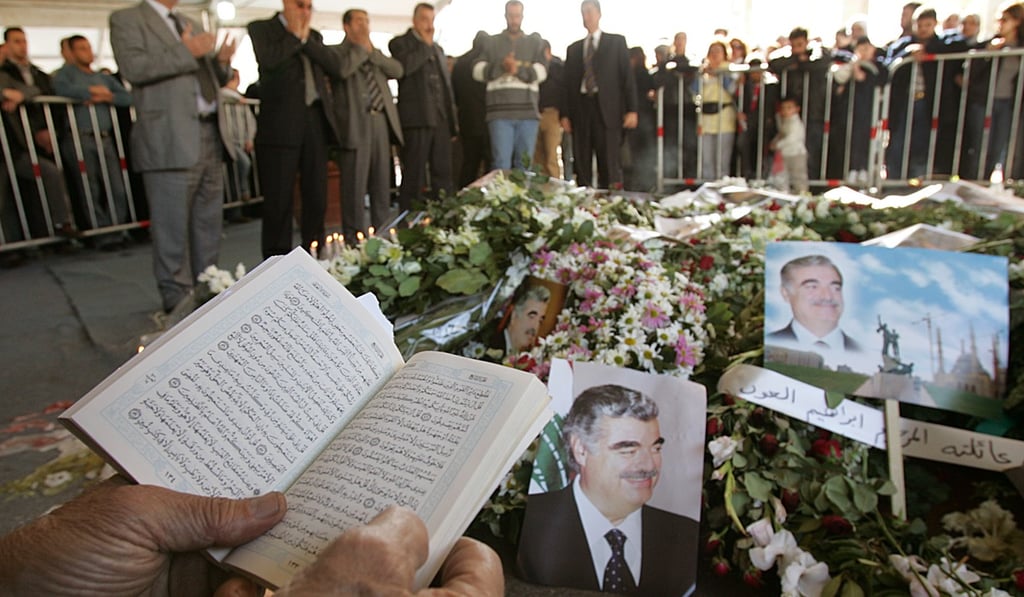 A Lebanese mourner reads verses of the Koran, Islam's holy book, while others pray in the background, at the grave of Lebanon's slain former prime minister Rafik Hariri in Beirut. File photo: AP