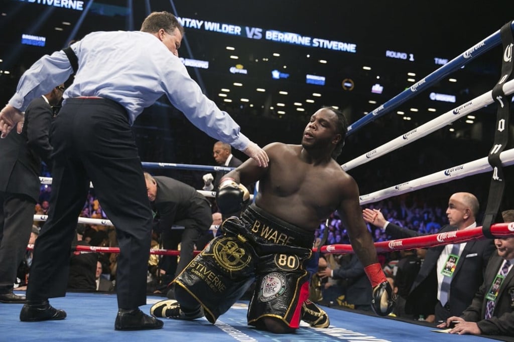 Stiverne is helped to his feet after being knocked down. Photo: AP Stiverne is helped to his feet after being knocked down. Photo: AP