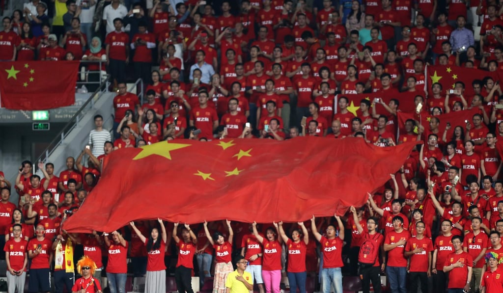 Football fans hold the Chinese national flag and sing the anthem. Photo: AFP