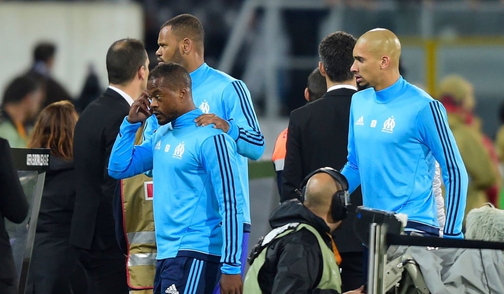 Patrice Evra is escorted off the pitch by teammates after the incident. Photo: AFP