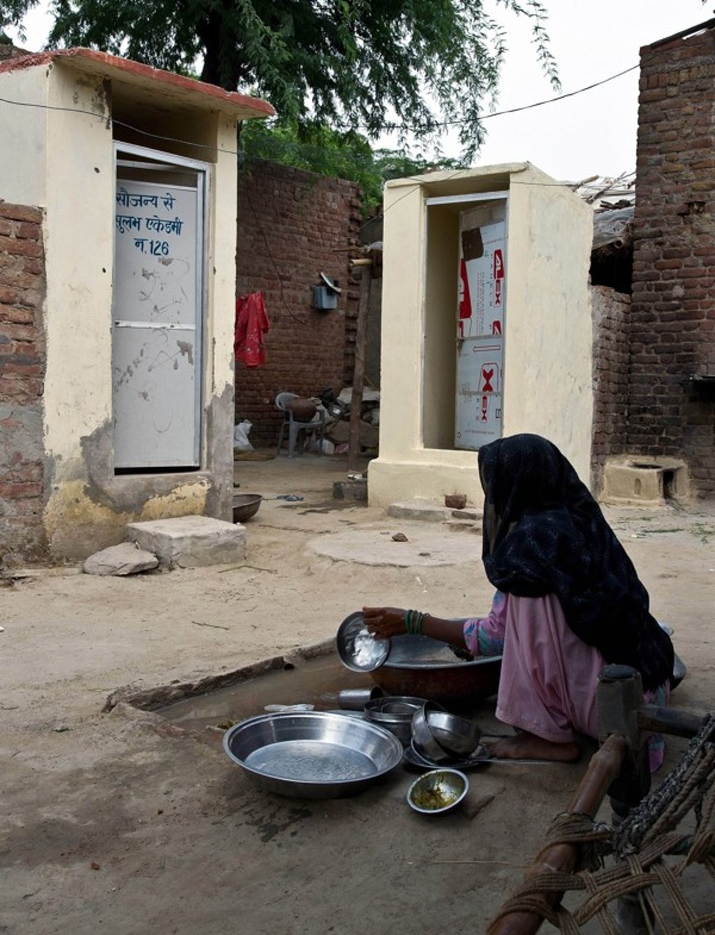 A woman washing pots near new toilets in a village in Haryana state. Photo: AFP